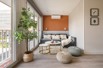 Stylish seating area with a terracotta color wall with a sofa and pouffes near the panoramic...