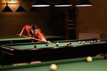 Sports game of billiards on a green cloth. Woman playing with Multi-colored billiard balls and cue on a pool table. Billiard sports
