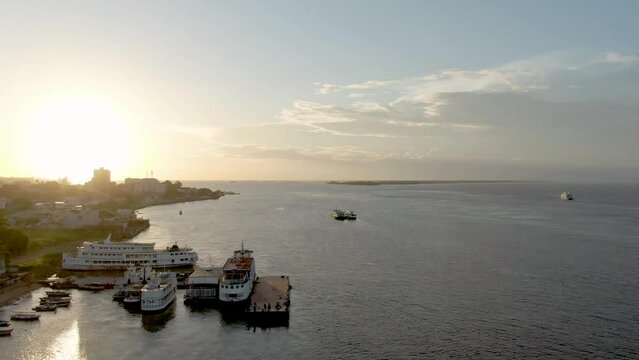 Aerial view passing river boats docked on the coast of Santarem, sunset in Brazil