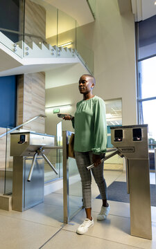 African american businesswoman with short hair entering from turnstile gate in office, copy space