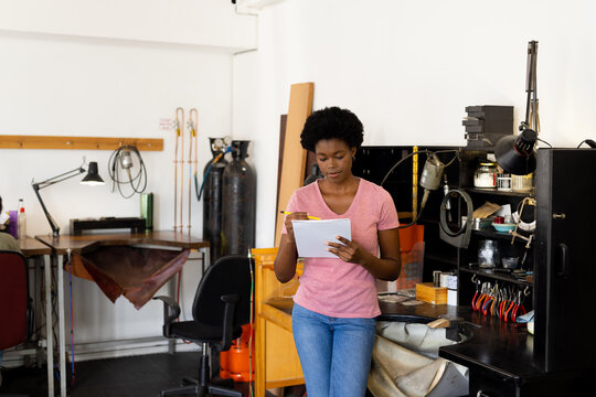 African american female worker drawing sketches in notebook at jewellery workshop