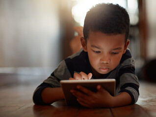 Learning, little boy and on digital tablet or playing games or streaming video on the internet and...