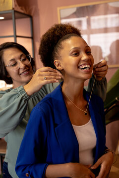 Diverse female jeweller and customers trying on necklace at jewellery shop