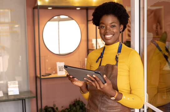 Portrait of happy african american female worker using tablet at jewellery shop