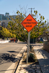 Image of a bright orange road construction ahead sign.