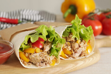 Delicious tortilla wraps with tuna on white wooden table, closeup