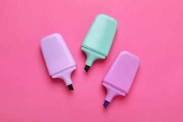 Colorful markers on pink background, flat lay
