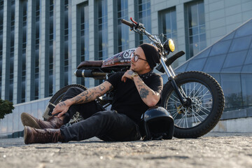 Obraz na płótnie Canvas Shot of individual motorcycle driver posing near huge city building.