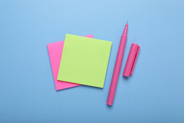 Paper notes and color marker on light blue background, flat lay
