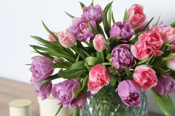 Beautiful bouquet of colorful tulip flowers near white wall, closeup