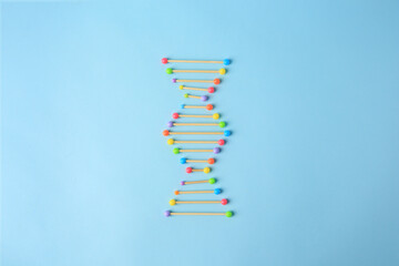 DNA molecule model made of toothpick and colorful beads on light blue background, flat lay