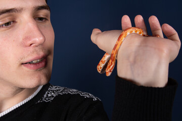 A man holds a small snake in his hands.