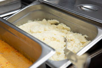 A view of a steamer tray full of grits, seen in a restaurant kitchen setting.