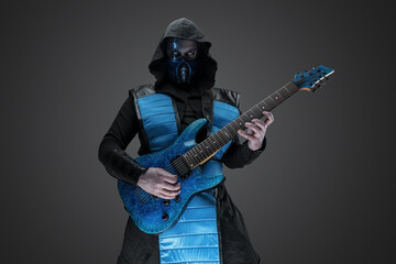 Shot of stealth assassin with guitar and hood staring at camera.