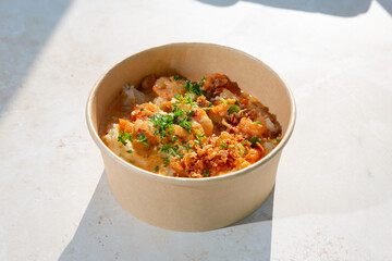 A view of an entree of shrimp and grits in a paper bowl container.