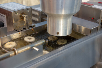 A view of some mini donuts being deep fried inside a small commercial automated donut making...