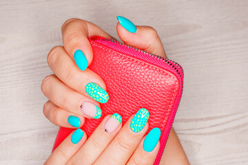 Turquoise nail art female manicure on a light wooden background