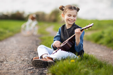 Pretty girl smiling playing ukulele in field
