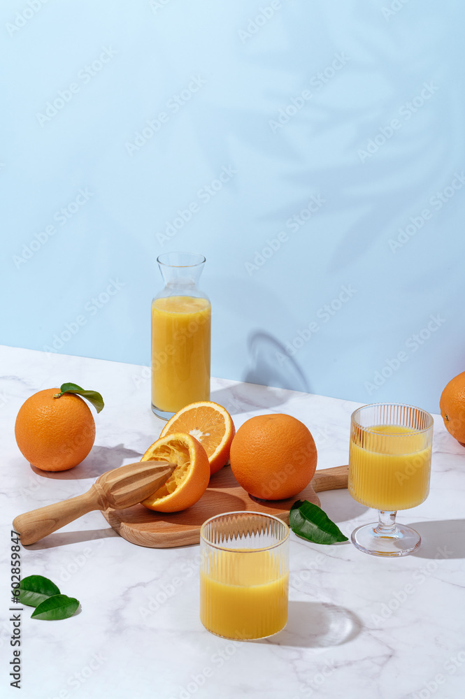 Wall mural fresh orange juice in a glass and decanter on a light table tabl