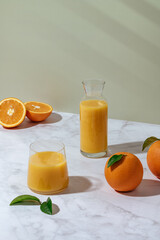 fresh orange juice in a glass and decanter. Oranges on the table