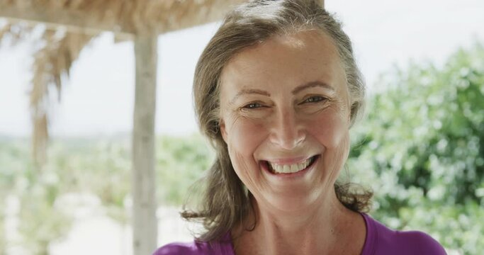Portrait of happy senior caucasian woman smiling on beach, in slow motion