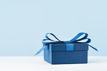 small Luxury gift box with a blue bow on light blue. Side view monochrome . Fathers day or...