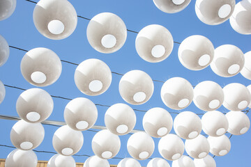 A view looking up at a pattern of hanging white balls as exterior design.