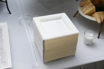 A view of a stack of elegant paper plates, part of a catered table.