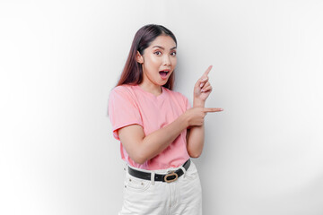 Shocked Asian woman wearing pink t-shirt, pointing at the copy space on beside her, isolated by white background