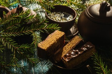 Christmas- still life with a piece of cake and morning tea. Fir tree branches- breakfast on a dark background
