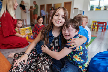 A girl and a boy with Down's syndrome in each other's arms spend time together in a preschool...