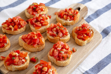 Homemade Italian Bruschetta Appetizer with Fresh Basil and Juicy Tomatoes on a Wooden Board, side view.