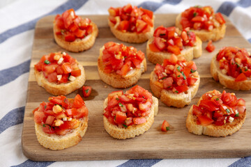 Homemade Italian Bruschetta Appetizer with Fresh Basil and Juicy Tomatoes on a Wooden Board, side view.
