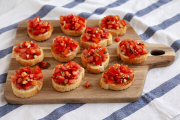 Homemade Italian Bruschetta Appetizer with Fresh Basil and Juicy Tomatoes on a Wooden Board, side view.