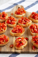 Homemade Italian Bruschetta Appetizer with Fresh Basil and Juicy Tomatoes on a Wooden Board, side view.