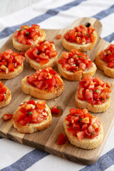 Homemade Italian Bruschetta Appetizer with Fresh Basil and Juicy Tomatoes on a Wooden Board, side view.