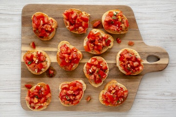 Homemade Italian Bruschetta Appetizer with Fresh Basil and Juicy Tomatoes on a Wooden Board, top view.