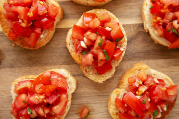 Homemade Italian Bruschetta Appetizer with Fresh Basil and Juicy Tomatoes on a Wooden Board, top view. Close-up.