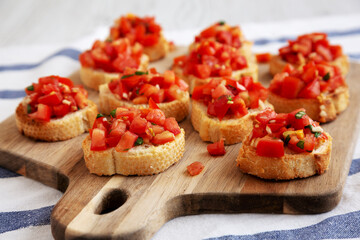 Homemade Italian Bruschetta Appetizer with Fresh Basil and Juicy Tomatoes on a Wooden Board, side view. Close-up.