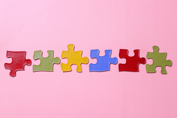 Multicolored pieces of puzzles isolated on pink background. Concept of autistic disorder. Autism awareness, Autism spectrum disorder family support concept. 