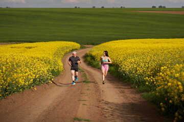 Obraz premium Endurance runners on a dirt track in a canola field, training