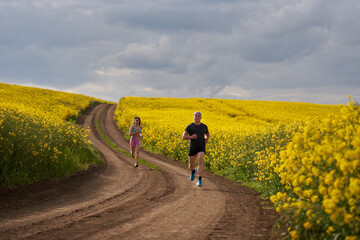 Endurance runners on a dirt track in a canola field, training