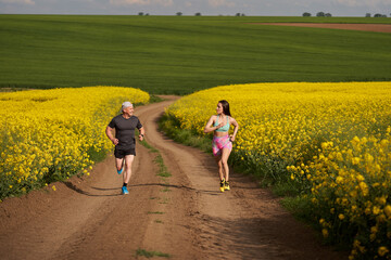 Obraz premium Endurance runners on a dirt track in a canola field, training