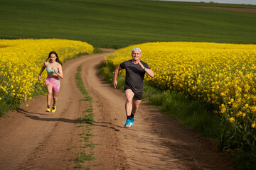 Obraz premium Endurance runners on a dirt track in a canola field, training