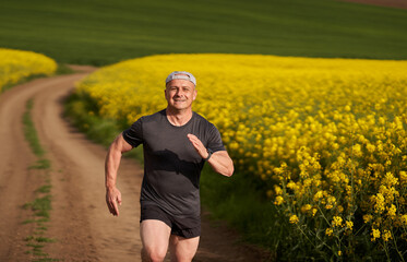 Distance runner running on a road through canola field