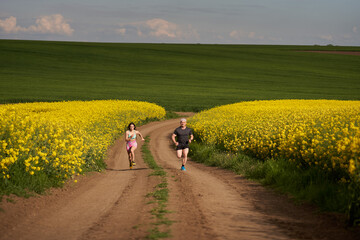 Endurance runners on a dirt track in a canola field, training