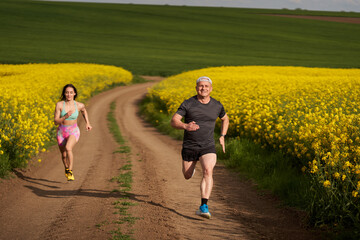 Obraz premium Endurance runners on a dirt track in a canola field, training