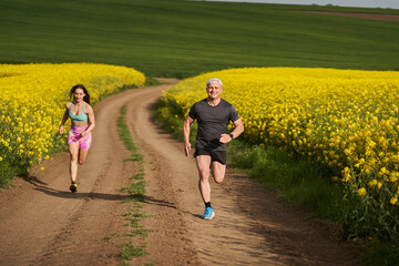 Fototapeta premium Endurance runners on a dirt track in a canola field, training