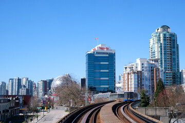 Obraz premium view from Sky Train window of moving train in Surrey in Vancouver spring no leaves bare trees stations skyscrapers technology centers rails Canada 2023