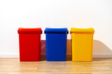 Three plastic trash bins against the wall in the building